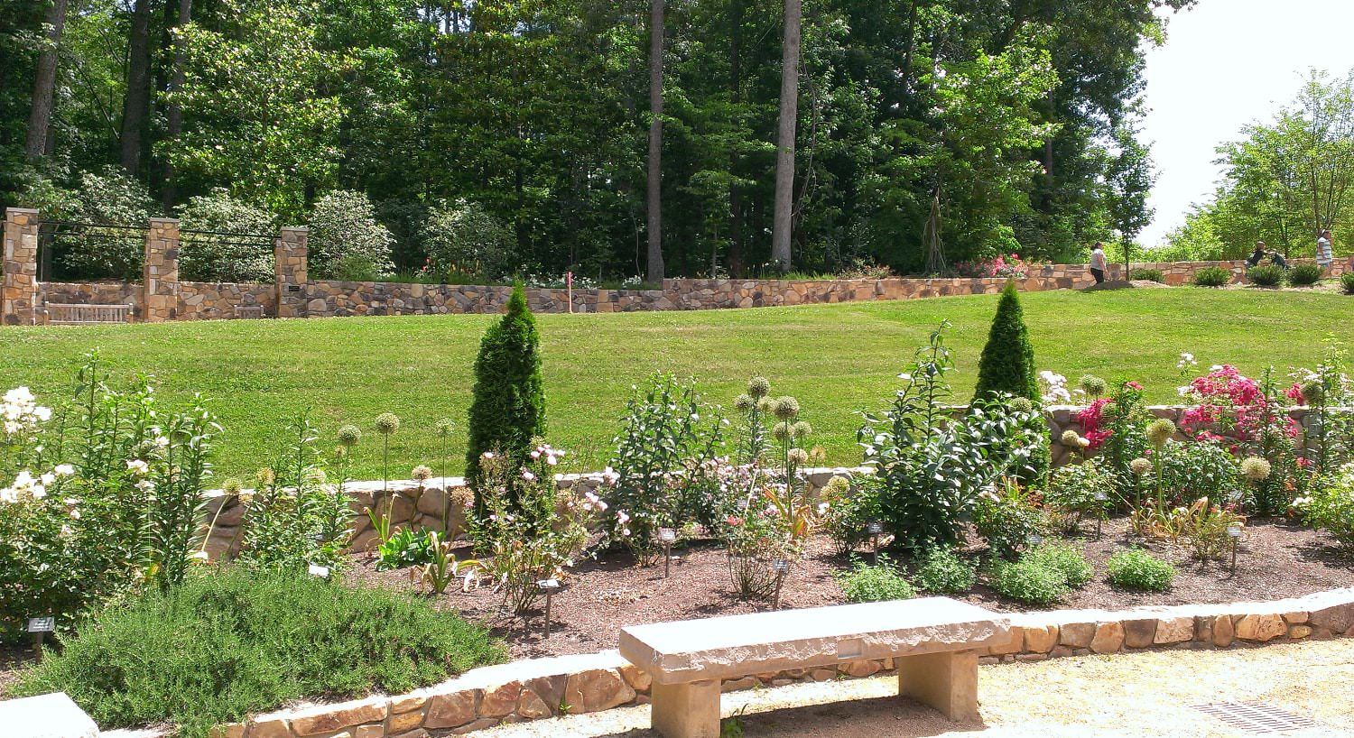 Stone brick flower garden with colorful flowers next to a large green lawn