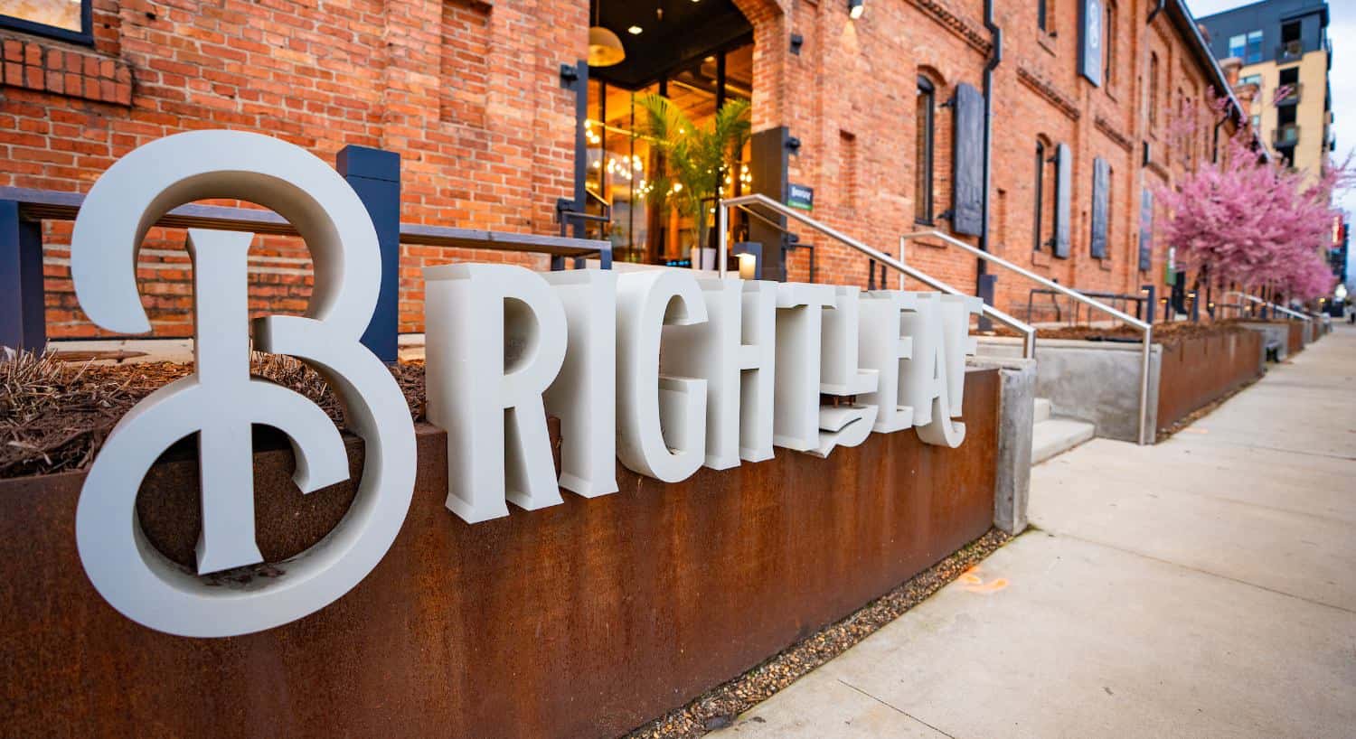Close up view of white Brightleaf sign in front of red brick building