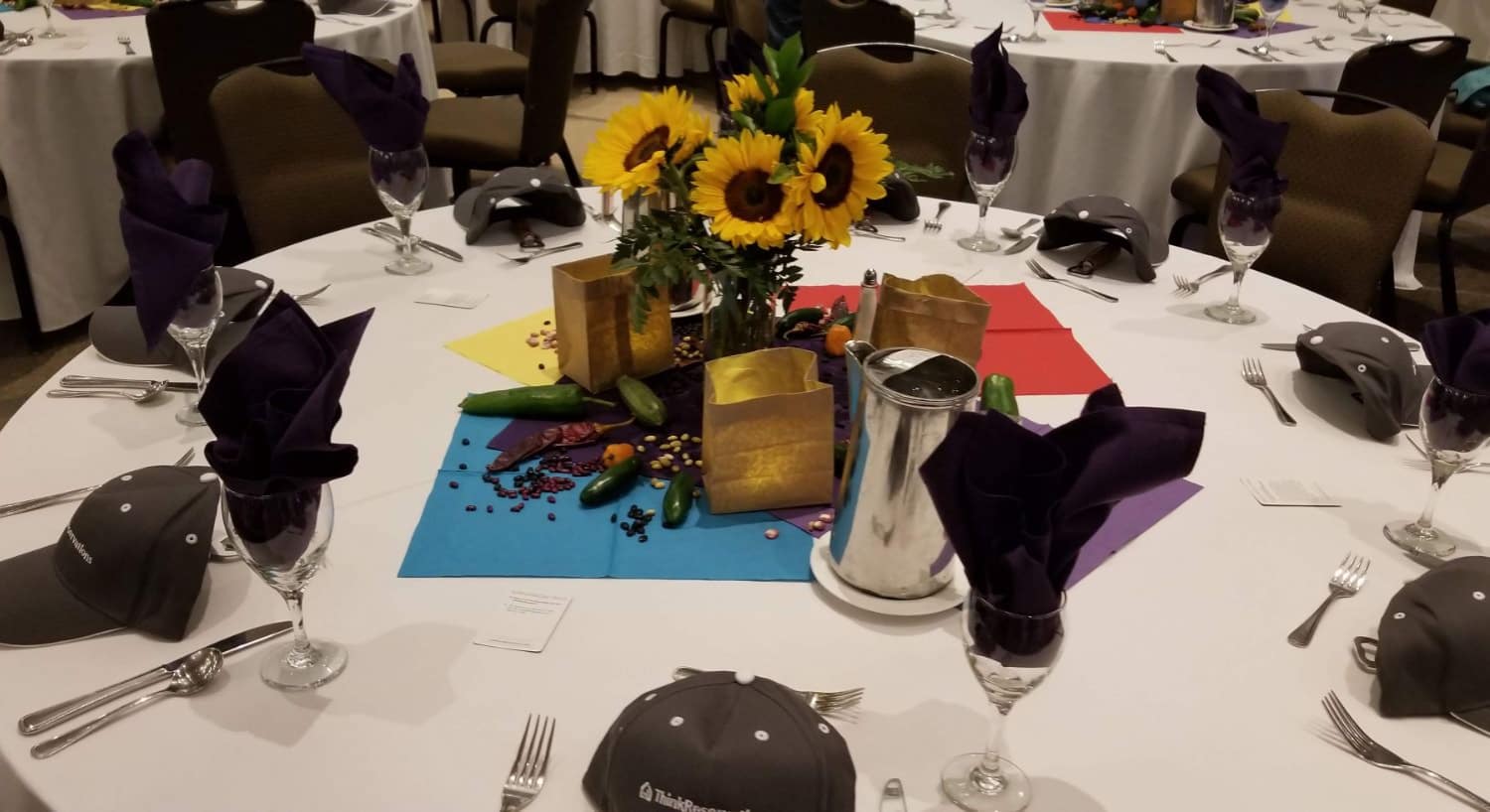 Corporate event table setting with branded baseball caps and place settings