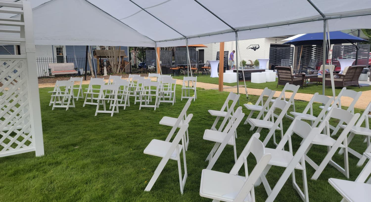 White event tent set up on a lawn with rows of chairs