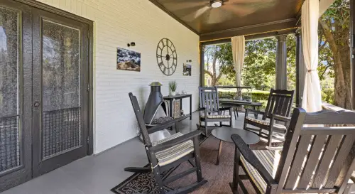 Front porch with dark gray wooden rocking chairs and small table