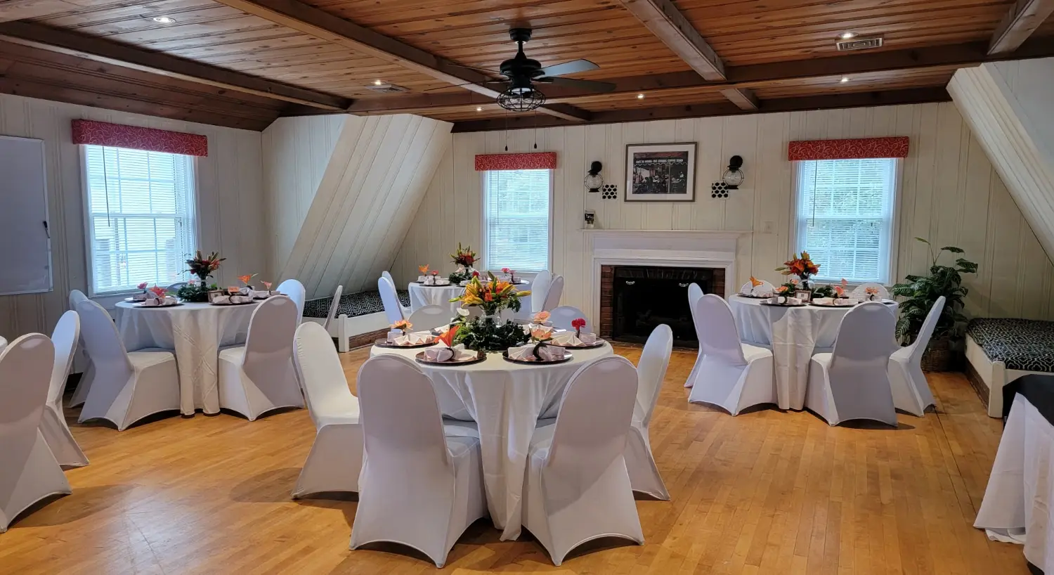 The Pecan Dining Room arranged with round tables, white linens, and colorful floral centerpieces