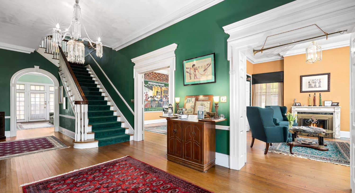 Front entrance hall with staircase, green walls, and views into adjoining rooms