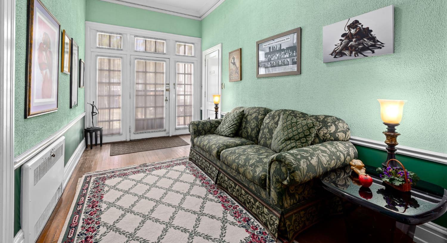 Interior of a parlor with green walls, floral couch, and art.