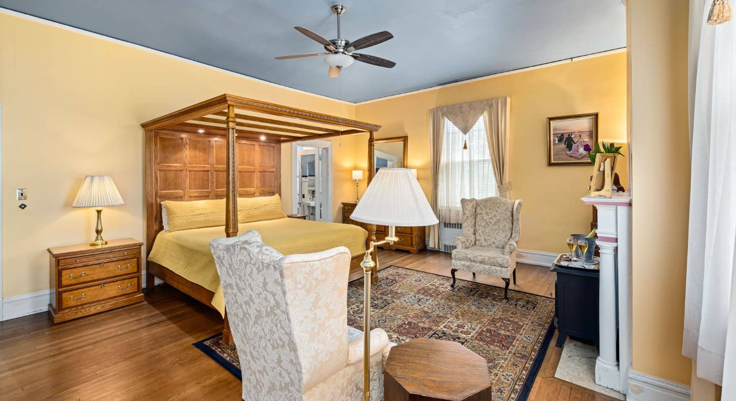The Magnolia Suite bedroom with canopy bed, yellow bedding, and sitting area