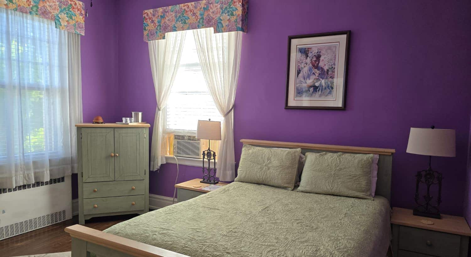 The Orchid Room bedroom with purple walls, sage green bedding, and wooden furniture