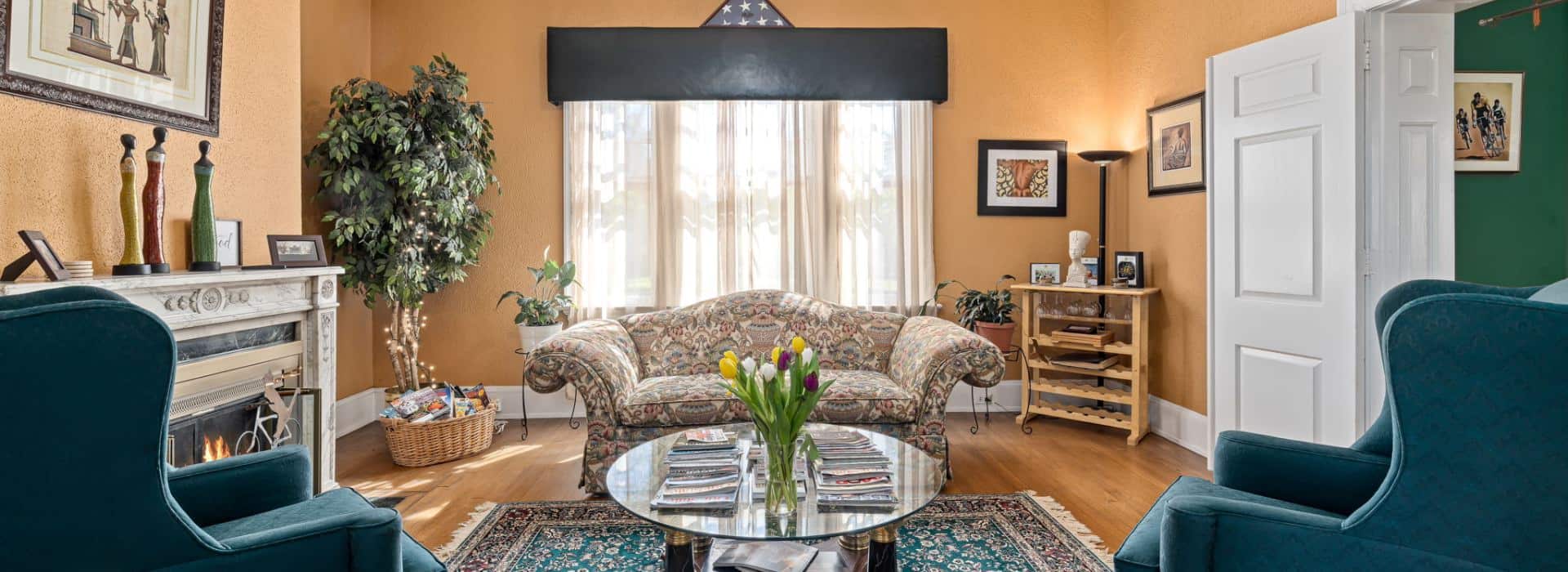 Living room at Morehead Manor with fireplace and teal armchairs