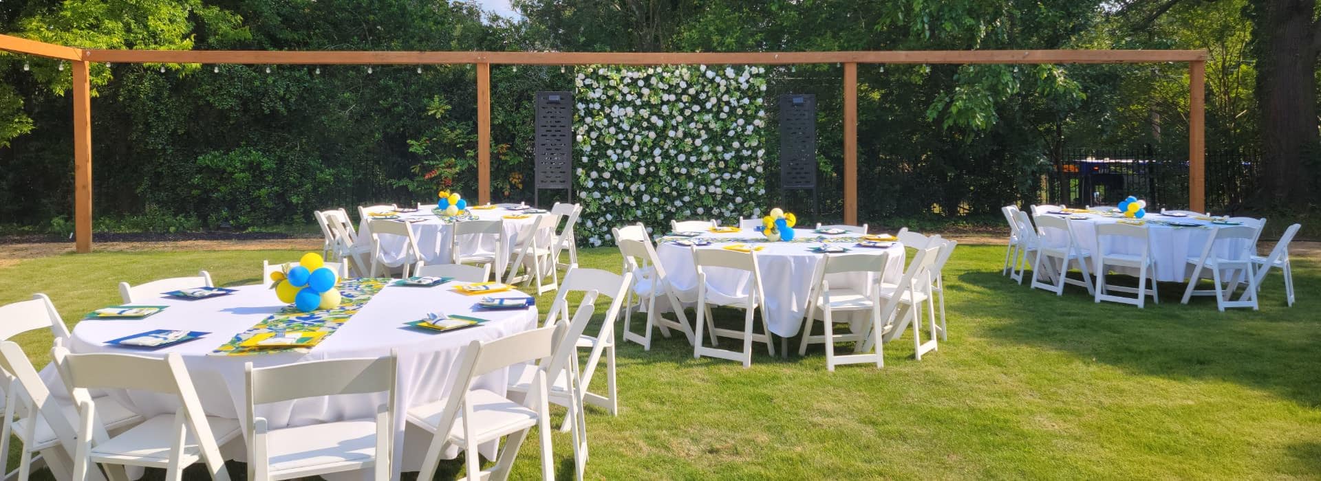 Outdoor event setup with round tables on a grassy lawn at Morehead Manor