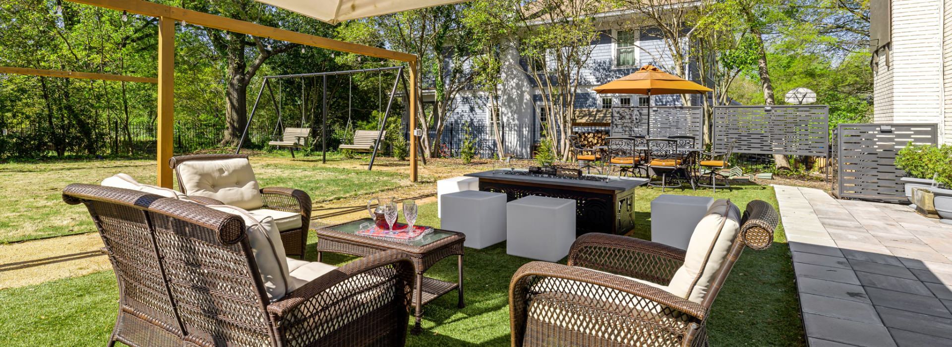 Backyard patio featuring wicker furniture, a fire pit, and swings