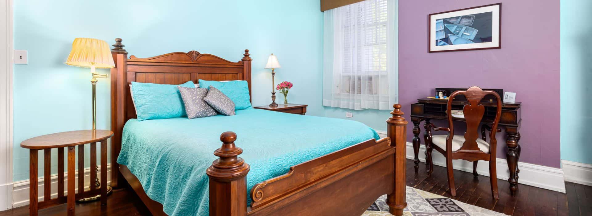 Bedroom with wooden furniture, turquoise bedding, and blue and purple walls