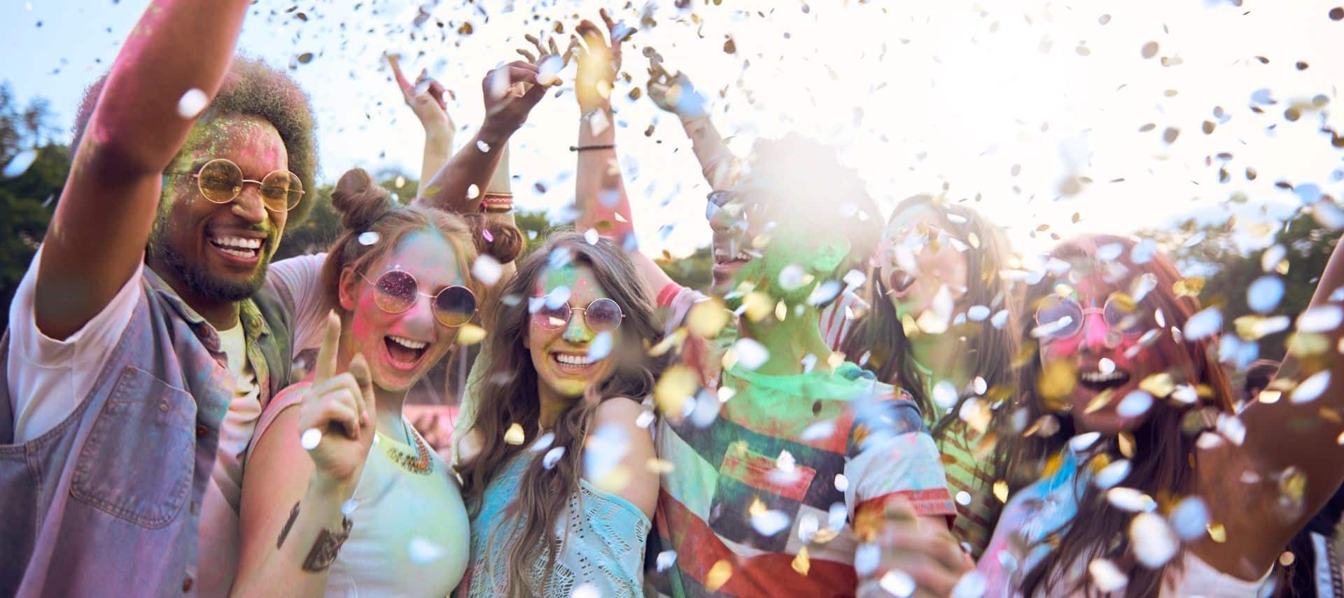Friends covered in colorful powder paint celebrating at a summer festival.