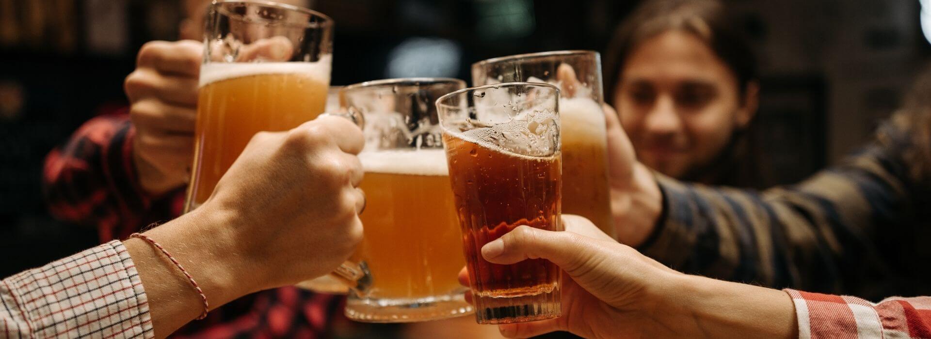 Group of friends clinking beer glasses together in a brewery.
