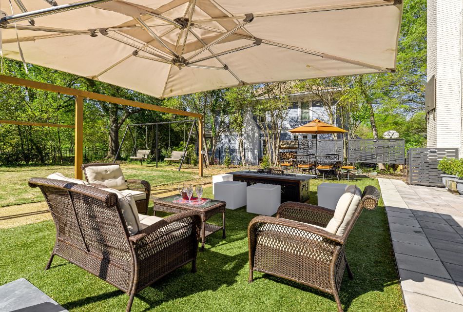 Backyard patio with wicker furniture, fire pit, and large green lawn