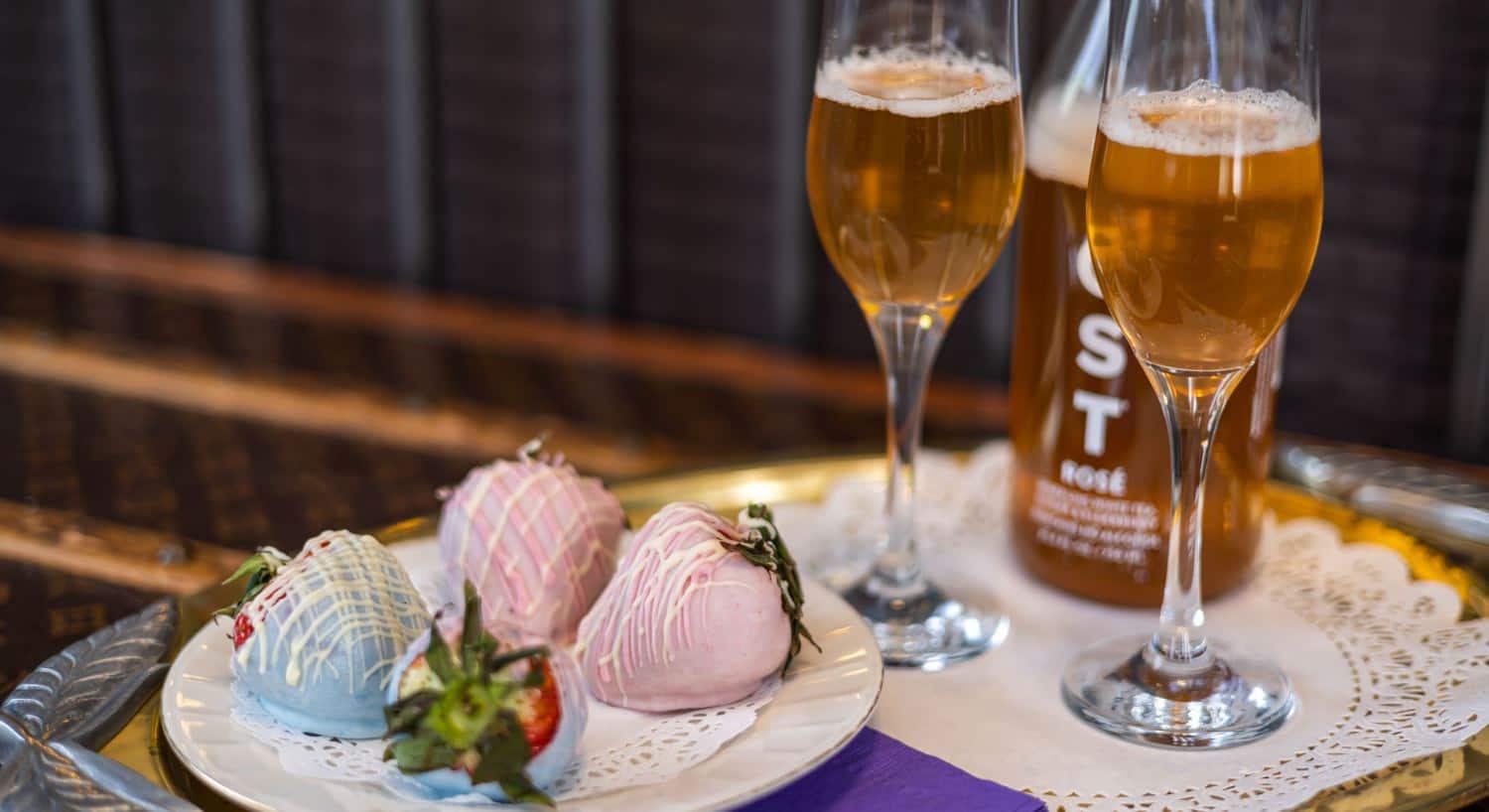 Blue and pink chocolate-covered strawberries and glasses of Rosé