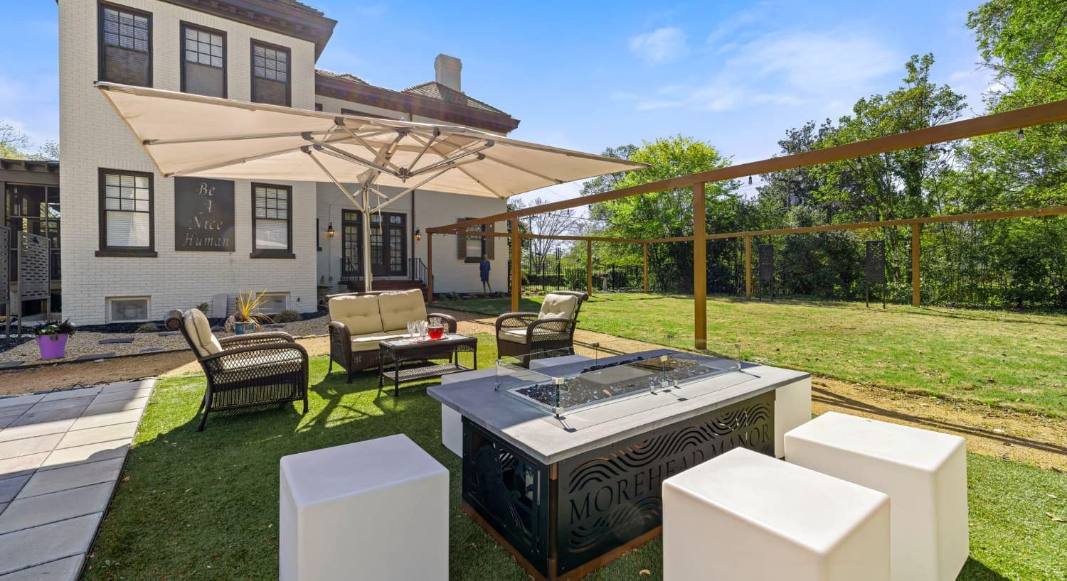 Backyard patio with wicker furniture, fire pit, and lawn
